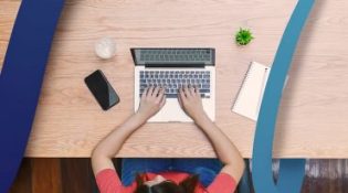 a woman sitting at a desk typing on a laptop